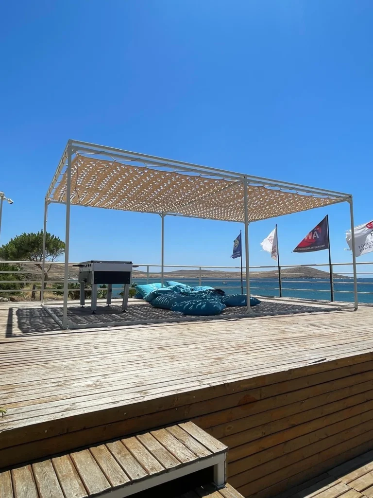 Çağla Kubat Windsurf Akademi, Alaçatı: ahşap terasta evcik modüler profil gölgelik
