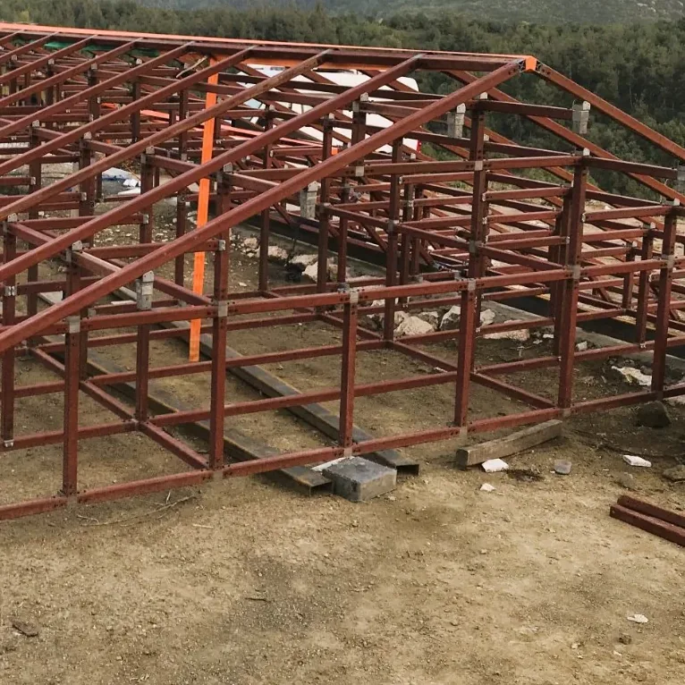 Kırsal bir arazide cıvatalı montajla kurulmuş kiremit renkli geniş çatı karkası